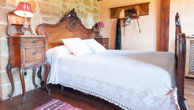 Habitación principal con cama antigua de madera y mesillas a juego