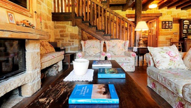 Escalera de madera hacia la galería superior del salón, junto a la chimenea de piedra