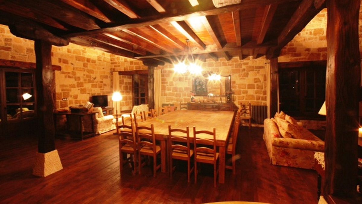 Salón comedor del caserío con vigas de madera vistas y mesa larga