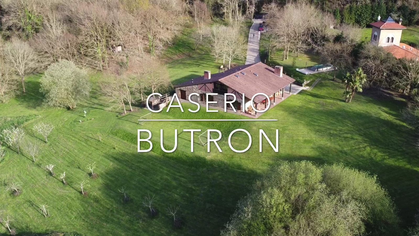Vista aérea de la finca del caserío Butrón, con la casa, el prado y los árboles alrededor
