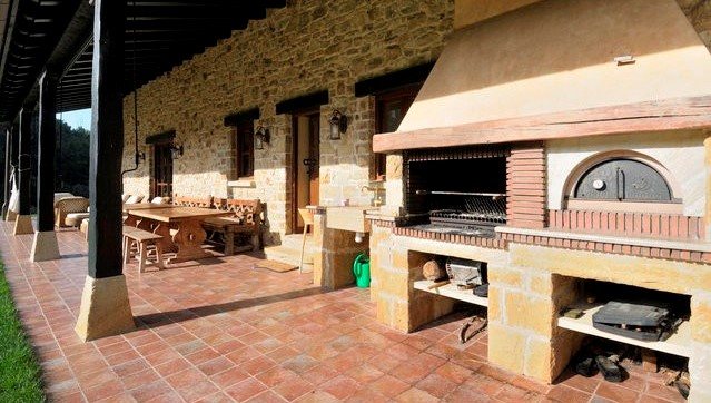 Barbacoa de piedra y horno de leña bajo el porche cubierto